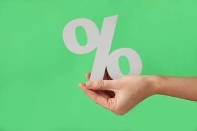 Woman holding percent sign on green background, closeup