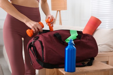 Woman packing sports stuff for training into bag at home, closeup