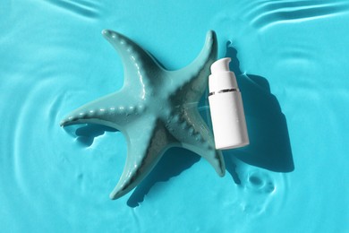 Moisturizing cream and sea star in water on light blue background, top view