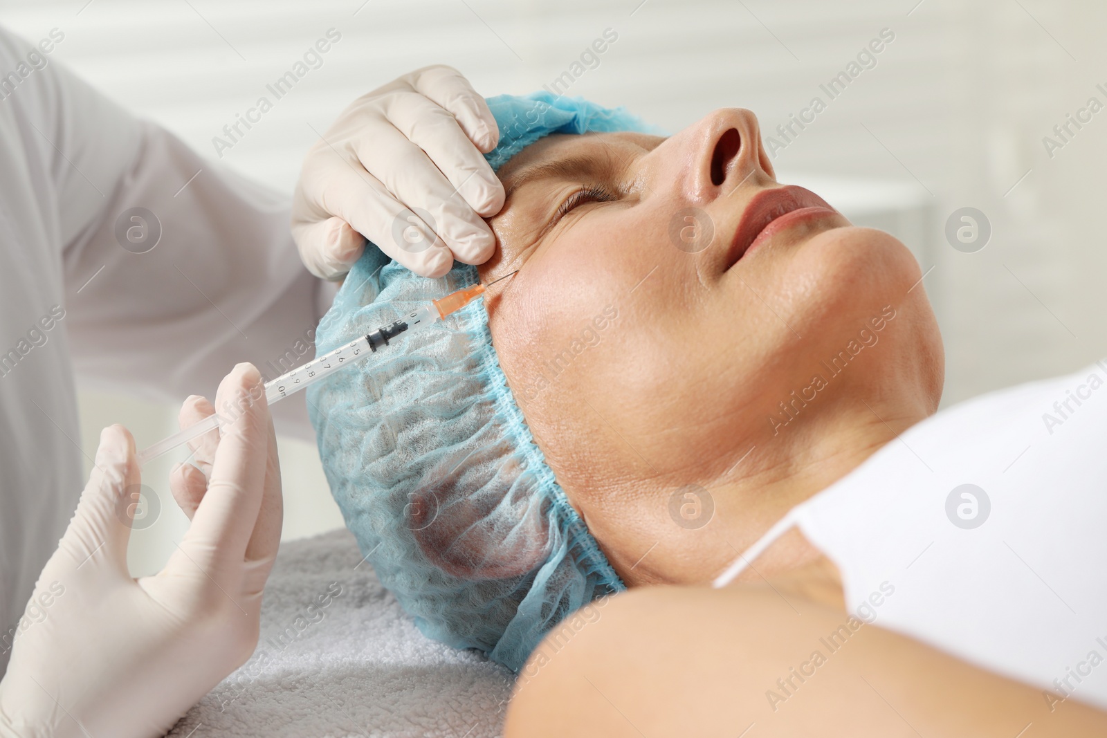 Photo of Doctor giving facial injection to senior woman in clinic, closeup. Cosmetic surgery