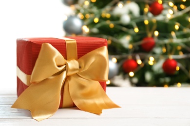 Beautiful gift box and blurred Christmas tree on background