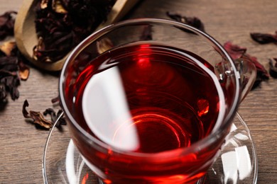 Cup of fresh hibiscus tea on wooden table, above view