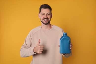 Photo of Man holding blue container of motor oil and showing thumbs up on orange background