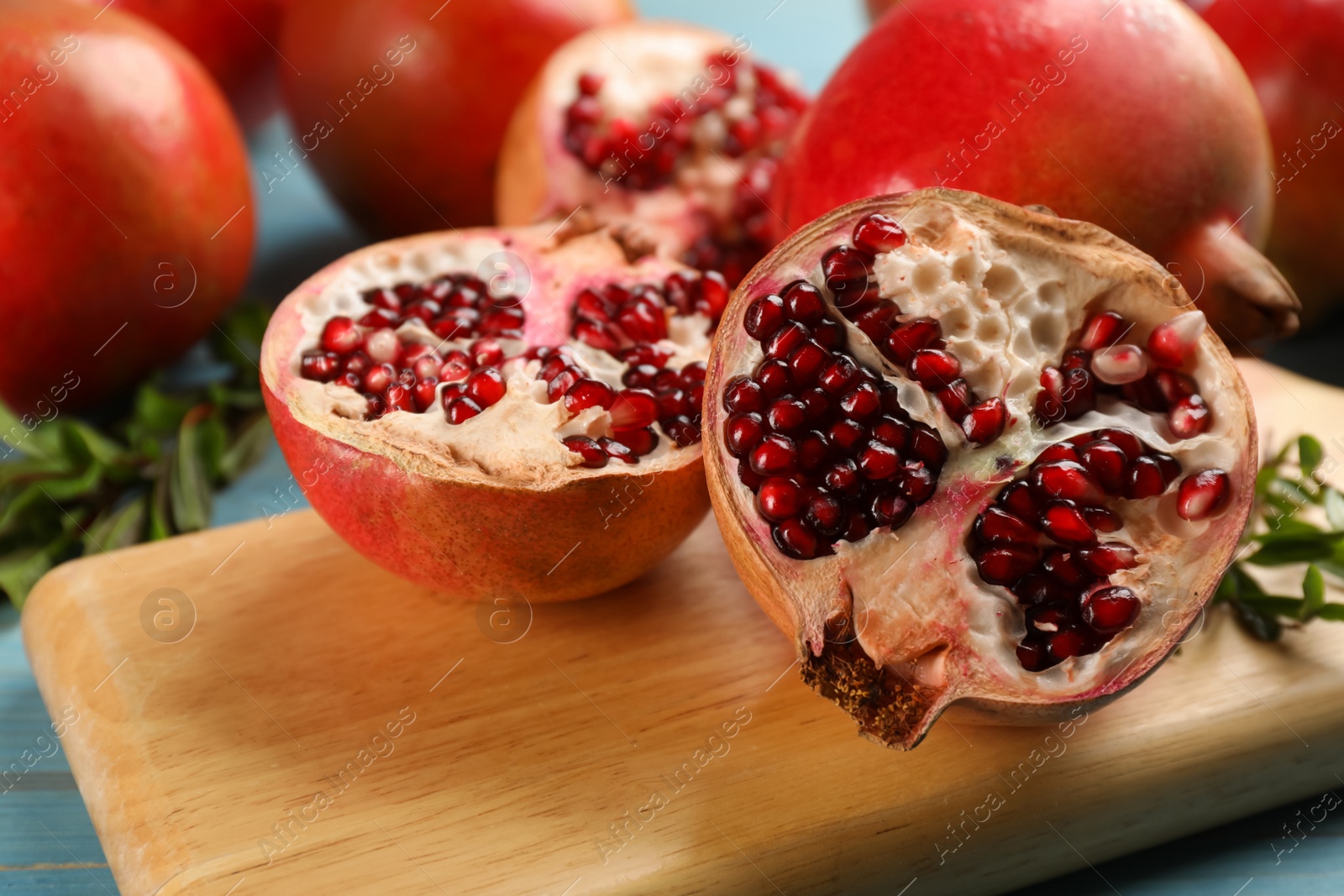 Photo of Cut ripe pomegranate on wooden board, closeup