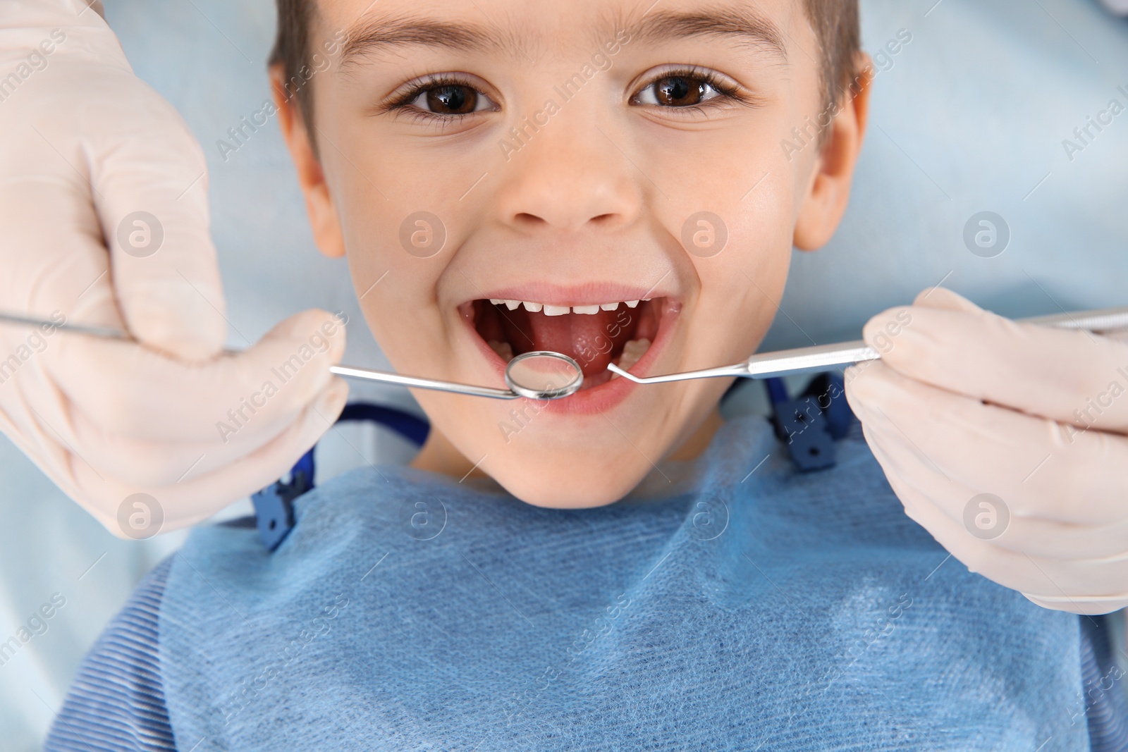 Photo of Dentist examining cute boy's teeth in modern clinic