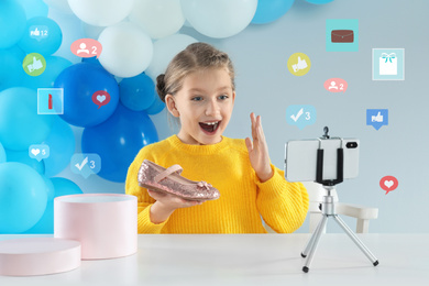 Image of Excited little blogger with shoes recording video at table