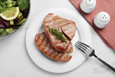 Photo of Delicious tuna steaks with rosemary and salad served on white marble table, flat lay