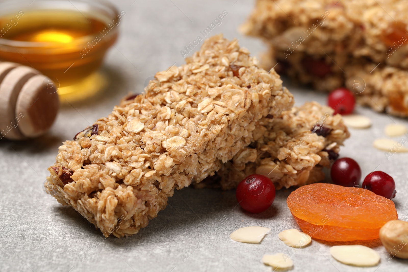 Photo of Tasty granola bars and ingredients on light grey table, closeup