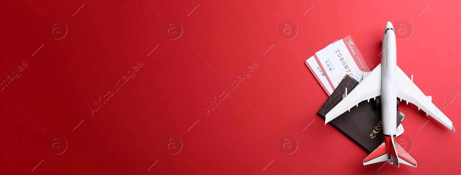 Photo of Toy airplane and passport with tickets on red background, flat lay. Space for text