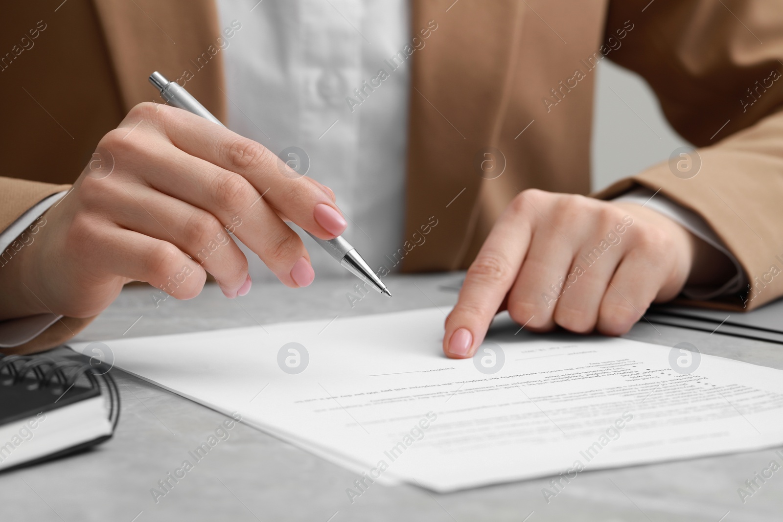 Photo of Woman signing document at light grey marble table, closeup