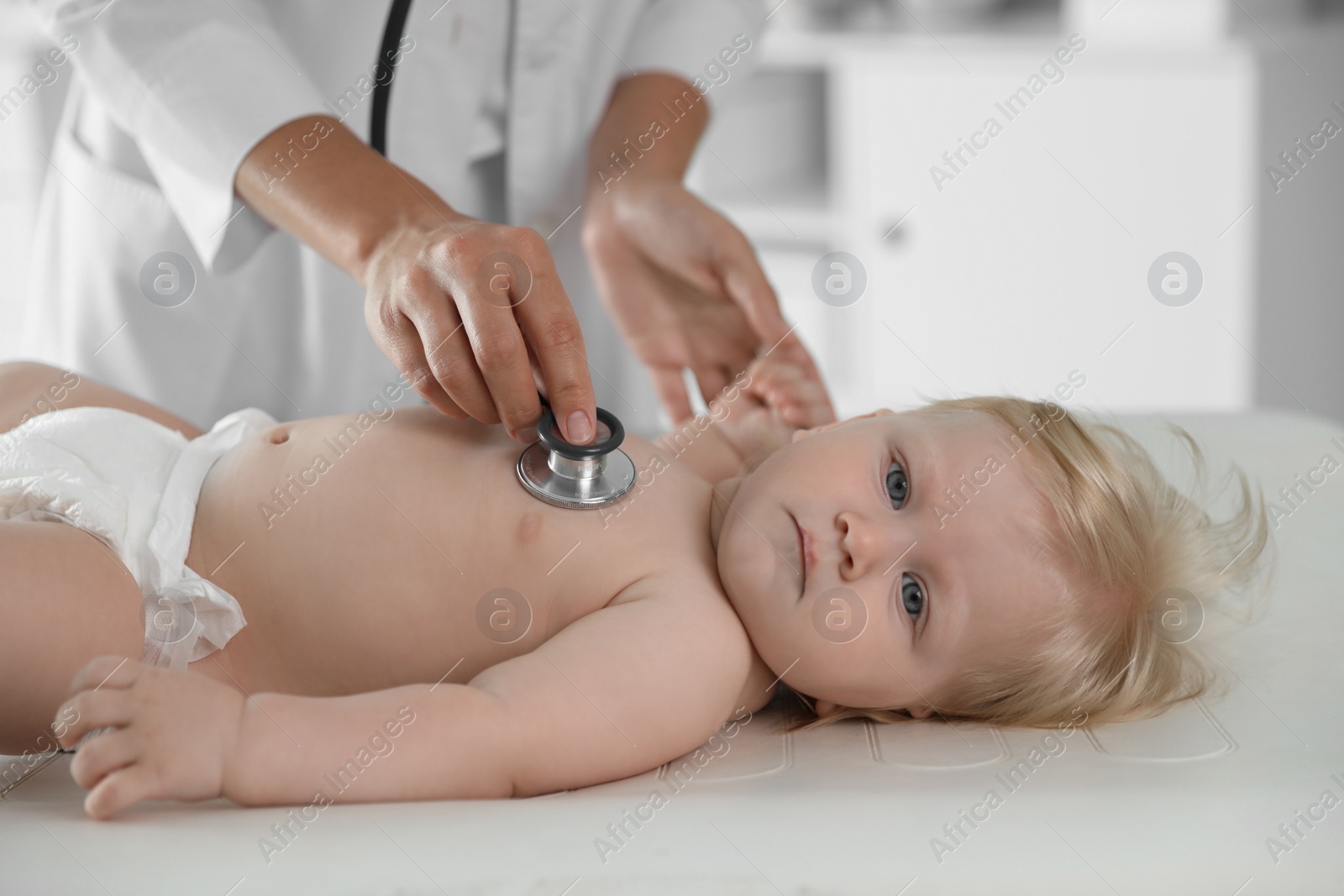 Photo of Pediatrician examining baby with stethoscope in hospital. Health care