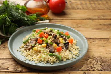 Delicious bulgur with vegetables and mushrooms on wooden table, closeup