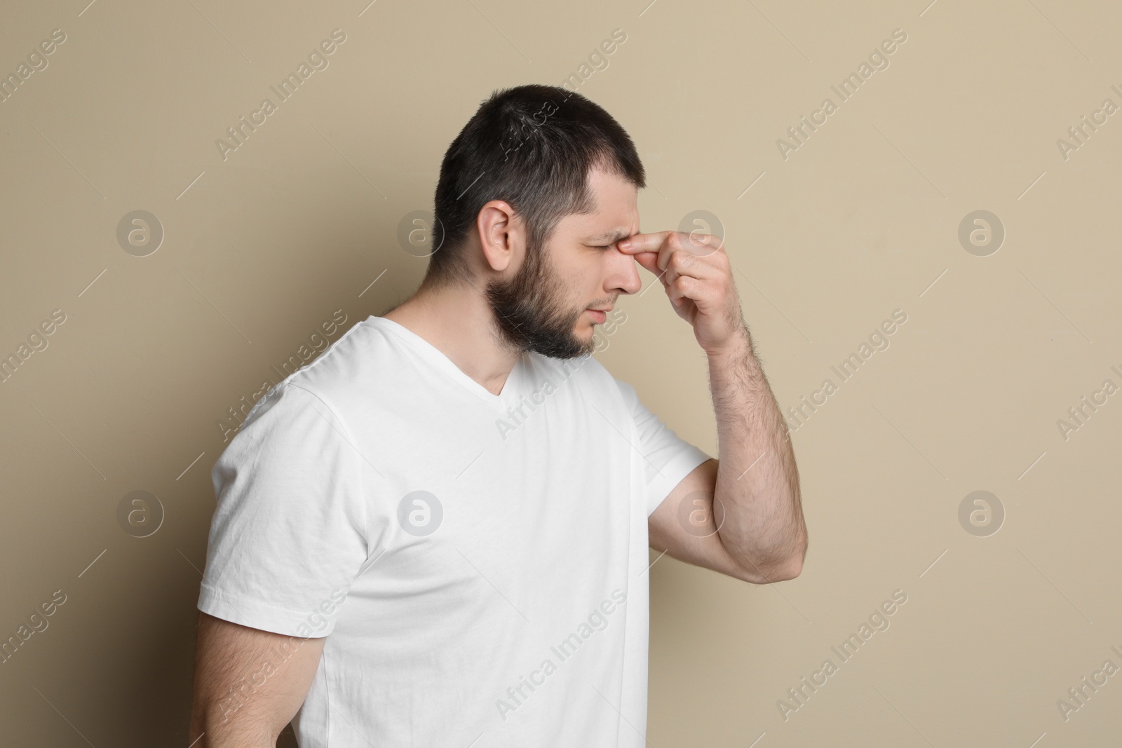 Photo of Man suffering from headache on beige background