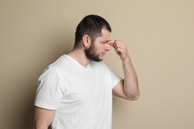 Photo of Man suffering from headache on beige background