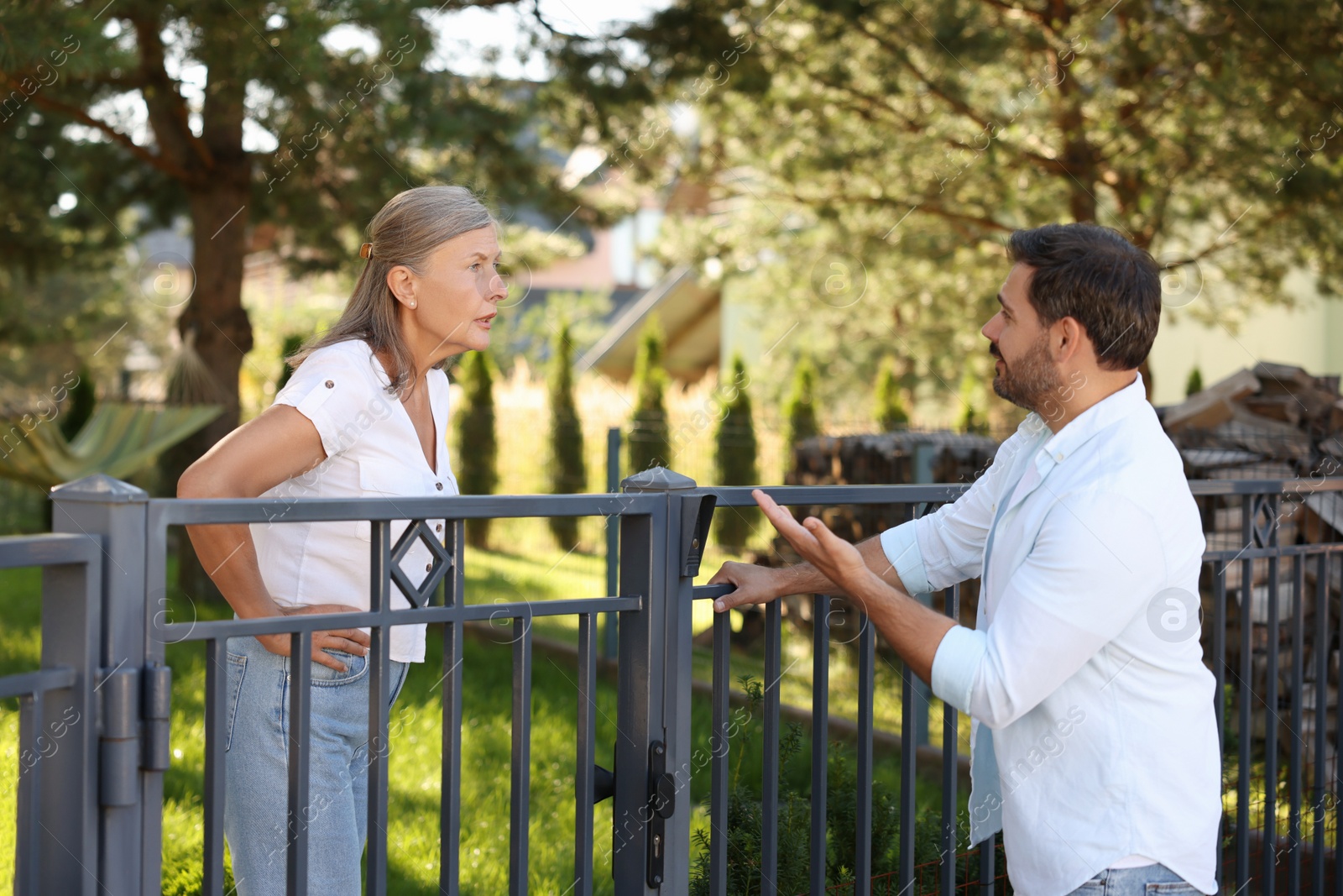 Photo of Emotional neighbours having argument near fence outdoors