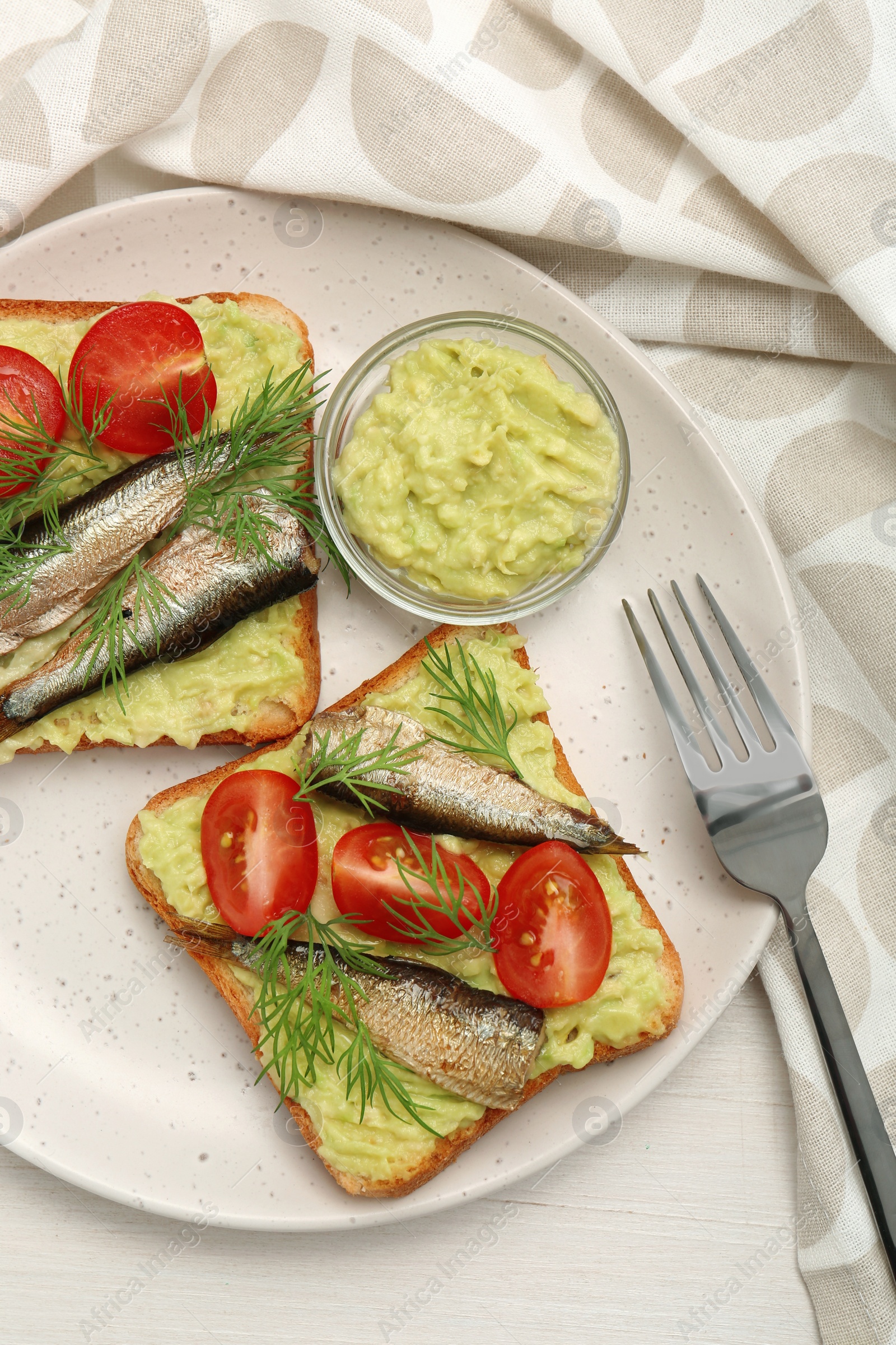Delicious sandwiches with sprats, tomatoes, dill and avocado puree served on white wooden table, top view Photo of Delicious sandwiches with sprats, tomatoes, dill and avocado puree served on white wooden table, top view