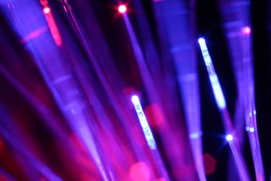 Photo of Optical fiber strands transmitting different color lights on black background, macro view
