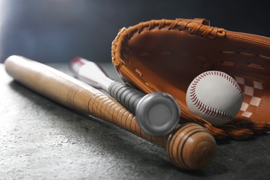 Baseball bats, glove and ball on grey table, closeup