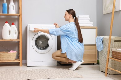 Photo of Beautiful woman near washing machine in laundry room