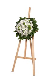 Funeral wreath of flowers on wooden stand against white background