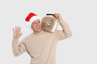 Emotional man with vintage radio on white background. Christmas music