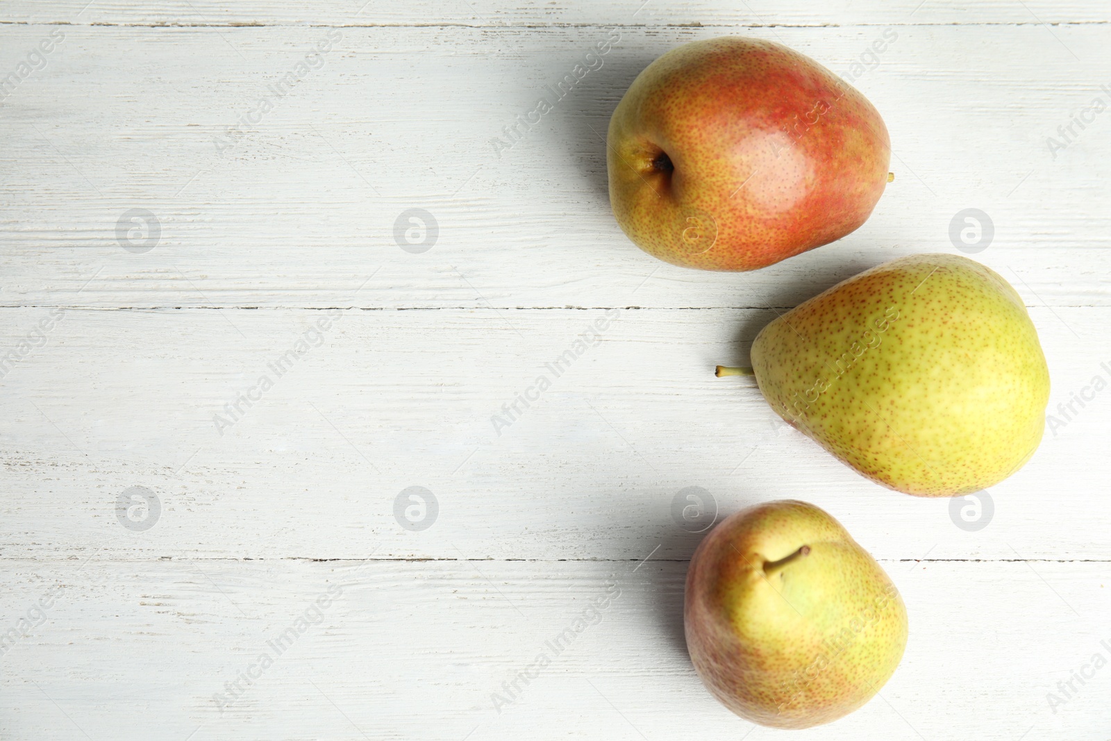 Photo of Ripe juicy pears on white wooden table, top view. Space for text