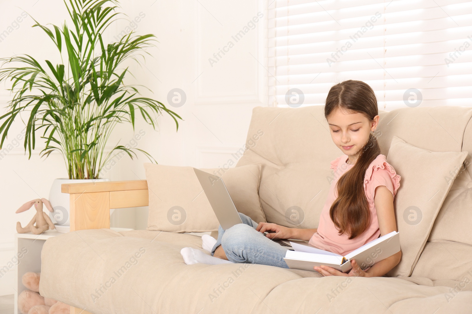 Photo of Girl with laptop and book on sofa at home