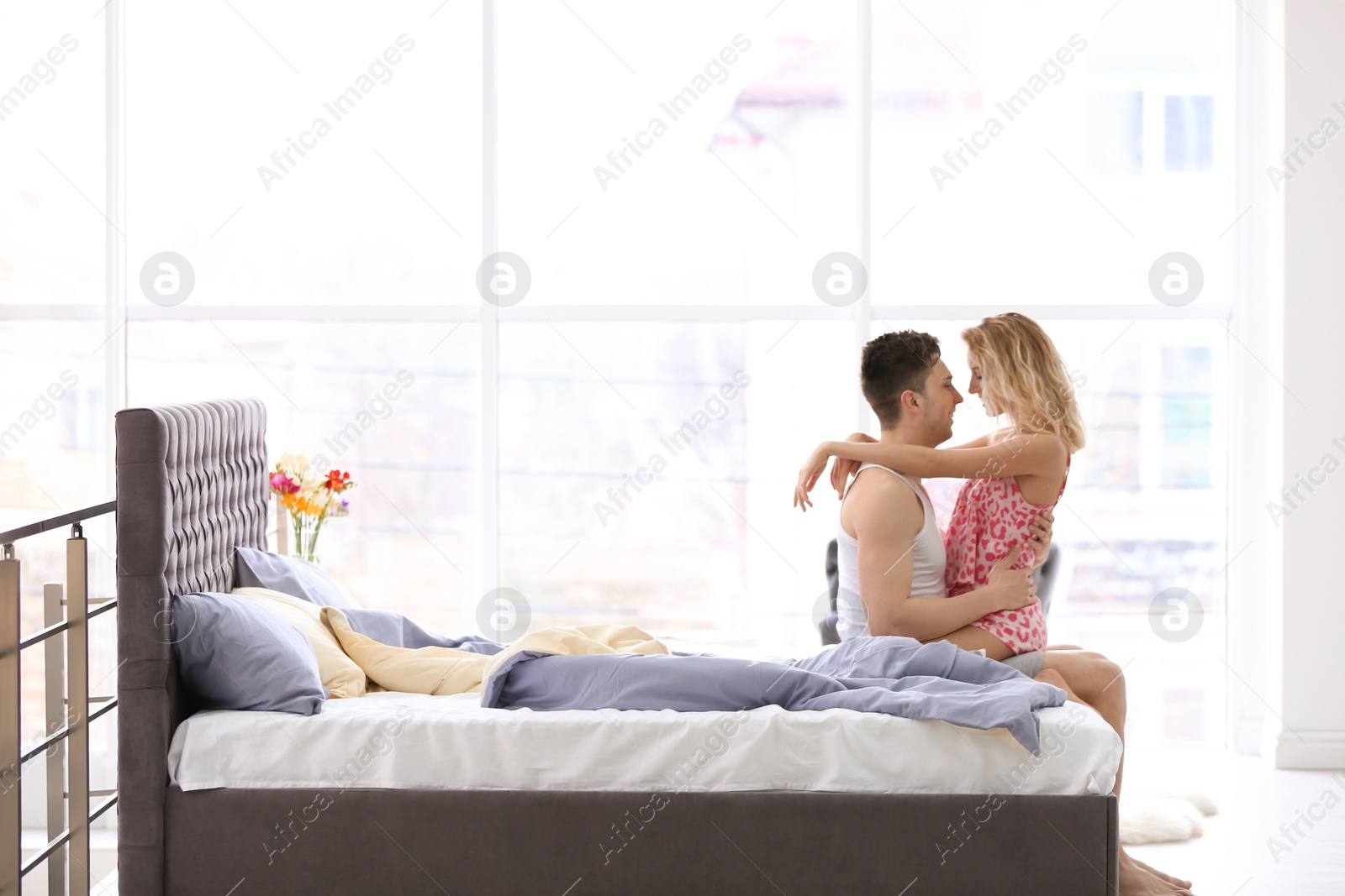 Photo of Happy young couple being intimate on bed at home