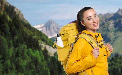 Image of Happy tourist with yellow backpack in mountains