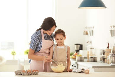 Mother and her daughter making dough at table in kitchen