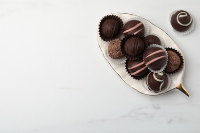 Photo of Delicious chocolate truffles on white marble table, flat lay. Space for text