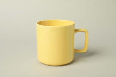 Photo of One yellow ceramic mug on light grey background