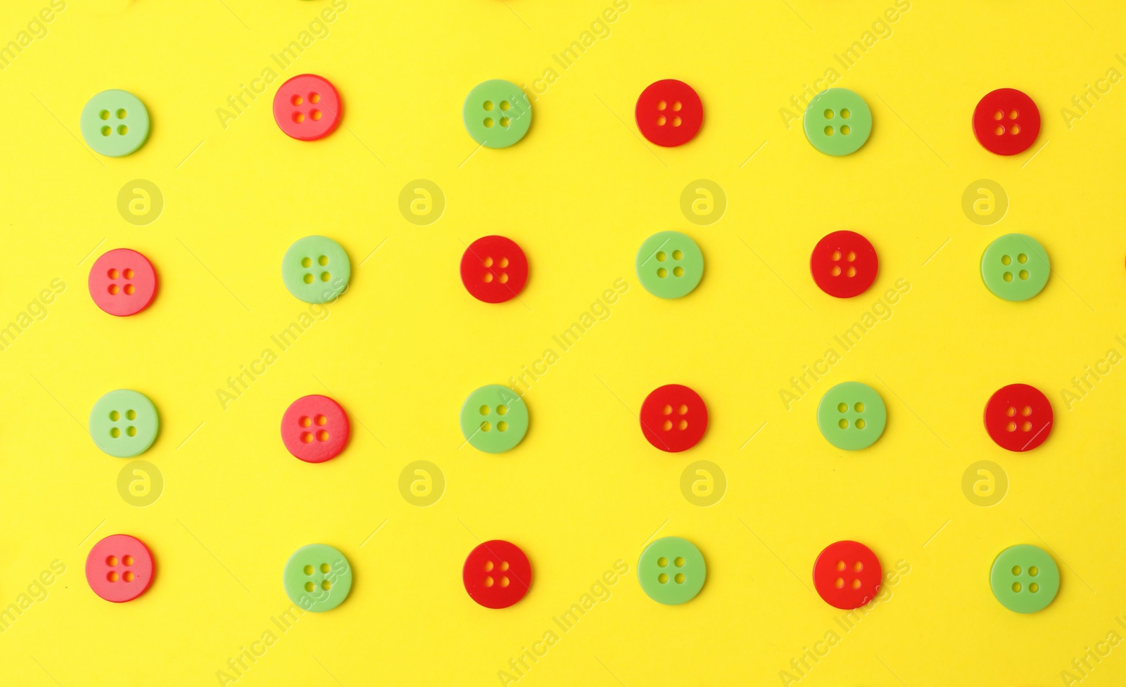 Photo of Many red and green sewing buttons on yellow background, flat lay