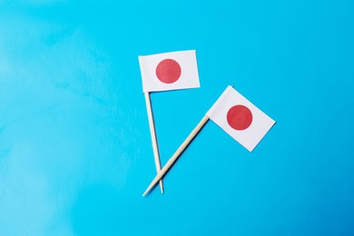Photo of Small paper flags of Japan on light blue background, flat lay