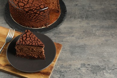 Photo of Delicious chocolate truffle cake and fork on grey textured table, space for text