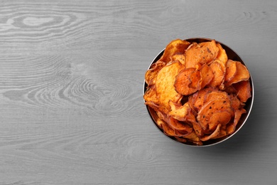 Bowl of sweet potato chips on grey table, top view. Space for text