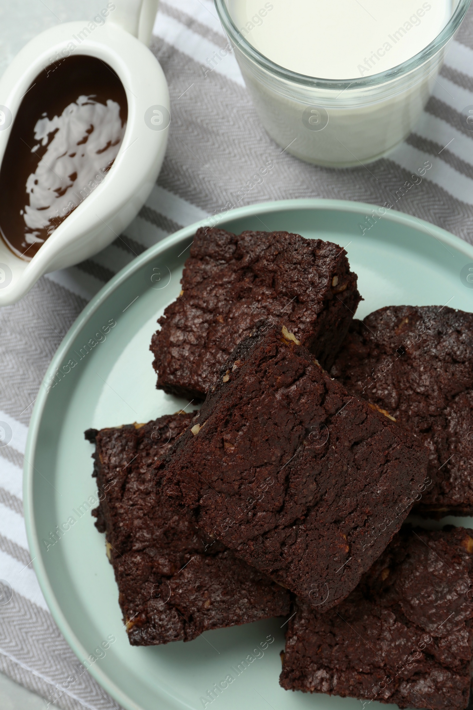 Photo of Delicious chocolate brownies with nuts on napkin fabric, flat lay