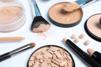 Composition with powder, skin foundation and beauty accessories on white background