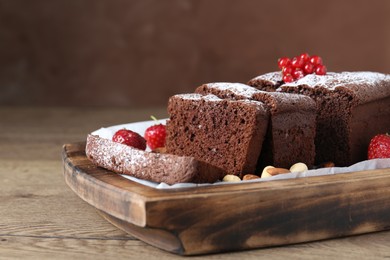 Tasty chocolate sponge cake with nuts and berries on wooden table, closeup. Space for text