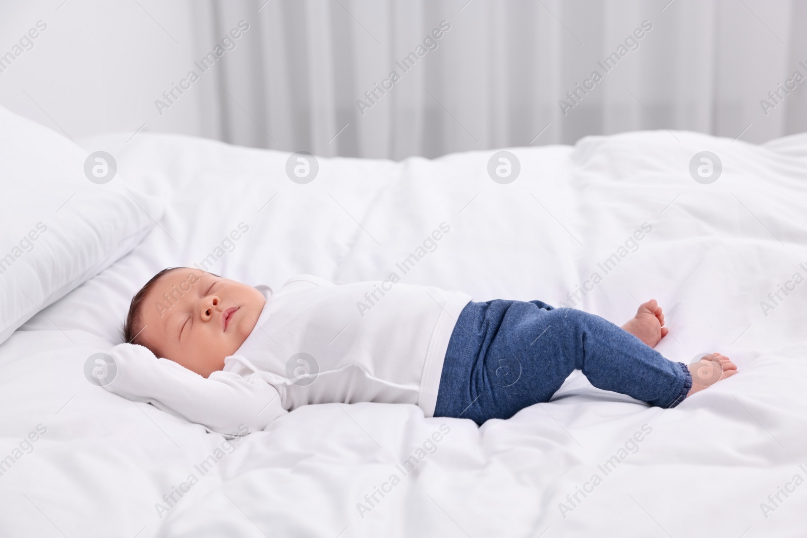 Photo of Cute newborn baby sleeping on white bed at home