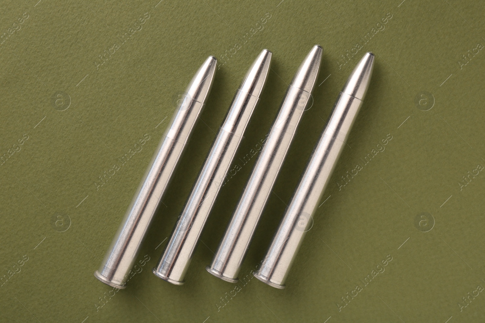 Photo of Many metal bullets on green background, flat lay