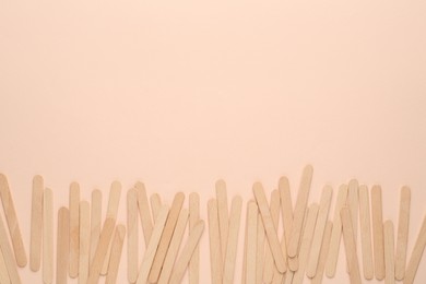 Photo of Wooden waxing spatulas on beige background, flat lay. Space for text