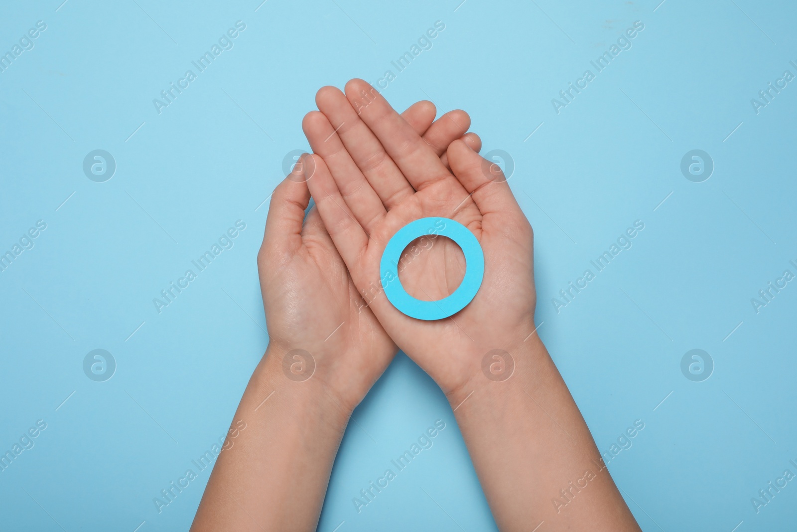 Photo of Woman showing blue paper circle as World Diabetes Day symbol on color background, top view