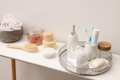 Photo of Different bath accessories and personal care products on table near white wall