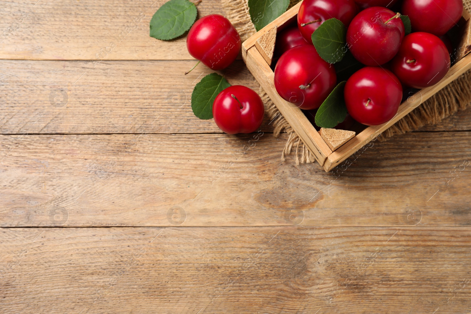 Photo of Fresh ripe cherry plums on wooden table, flat lay. Space for text