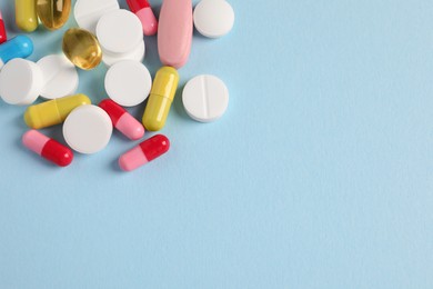 Photo of Pile of colorful pills on light blue background, flat lay. Space for text