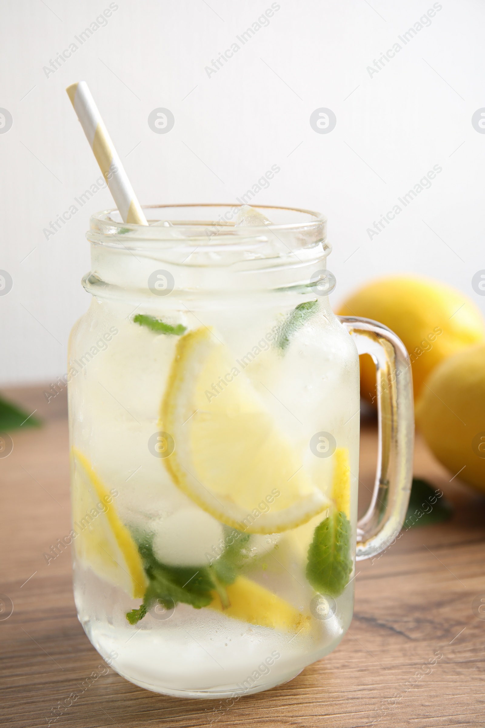 Photo of Mason jar of cold lemonade on wooden table