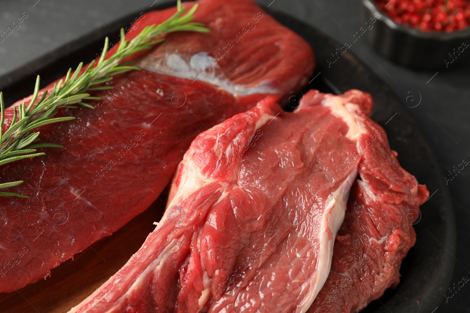 Photo of Pieces of raw beef meat and spices on grey table, closeup