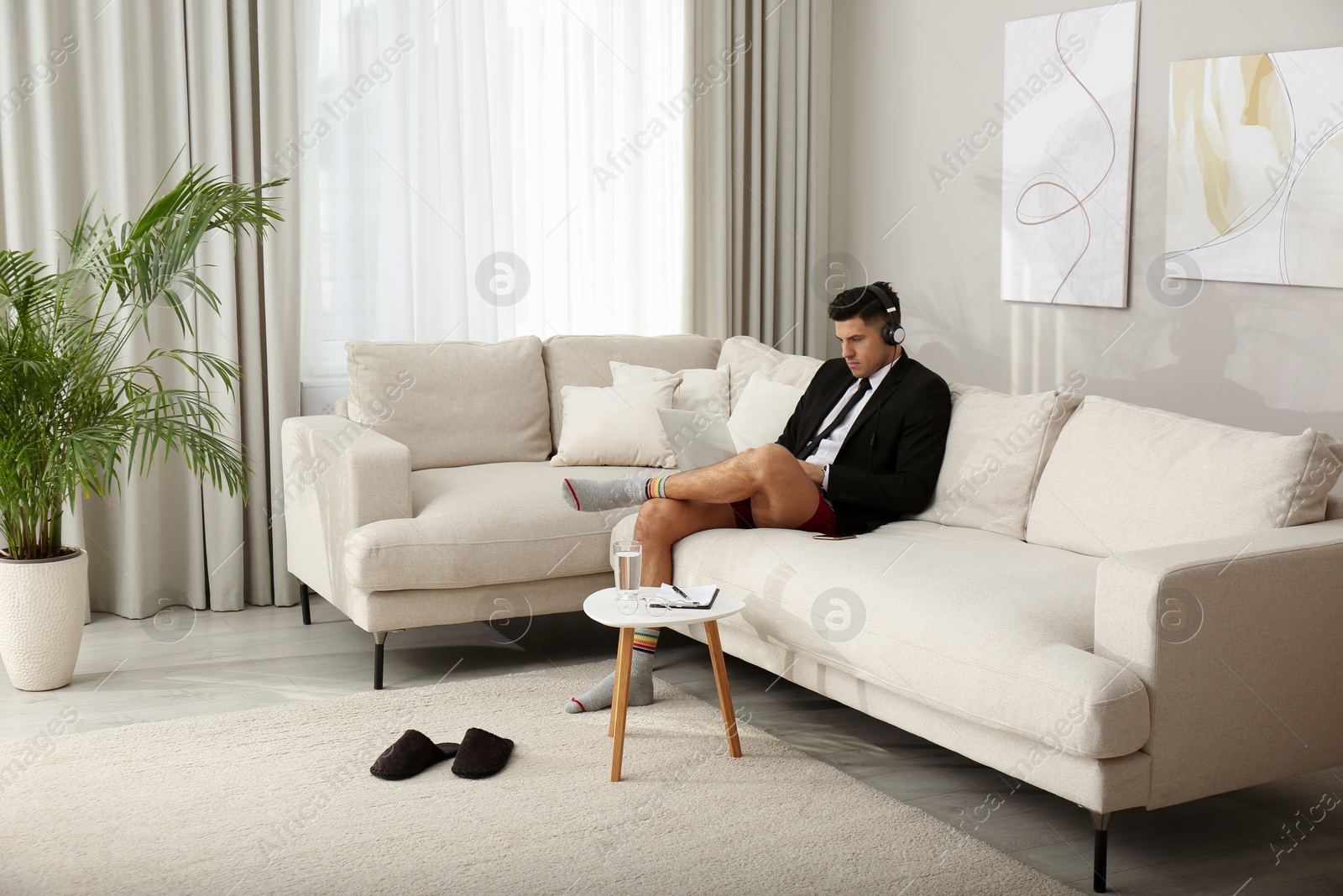 Photo of Businessman in jacket and underwear working on laptop at home