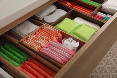 Photo of Storage of different feminine hygiene products in wooden drawer, closeup